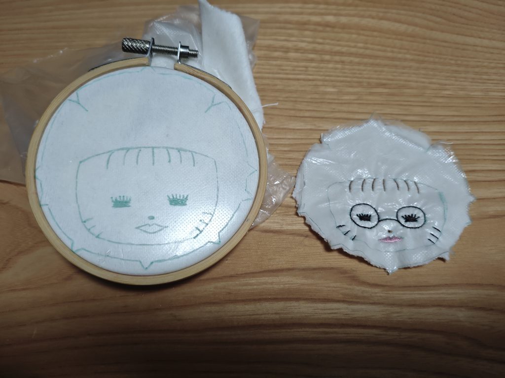 刺繍枠に張られた布と、刺繍が済んだ顔のパーツ